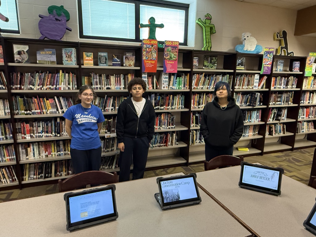 3 students standing in front of 3 computers proudly displaying their projects for History Fair