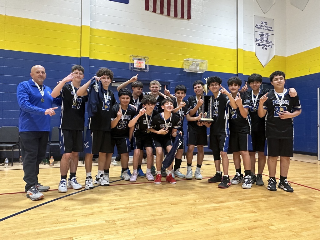 Boys volleyball team standing together on a gym court, smiling and celebrating as they hold up a championship trophy, with teammates gathered closely around and a sense of excitement and accomplishment visible on their faces.