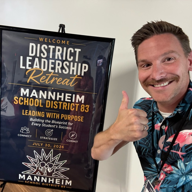 man with thumbs up, in Hawaiian shirt, in front of poster for District 83 Retreat