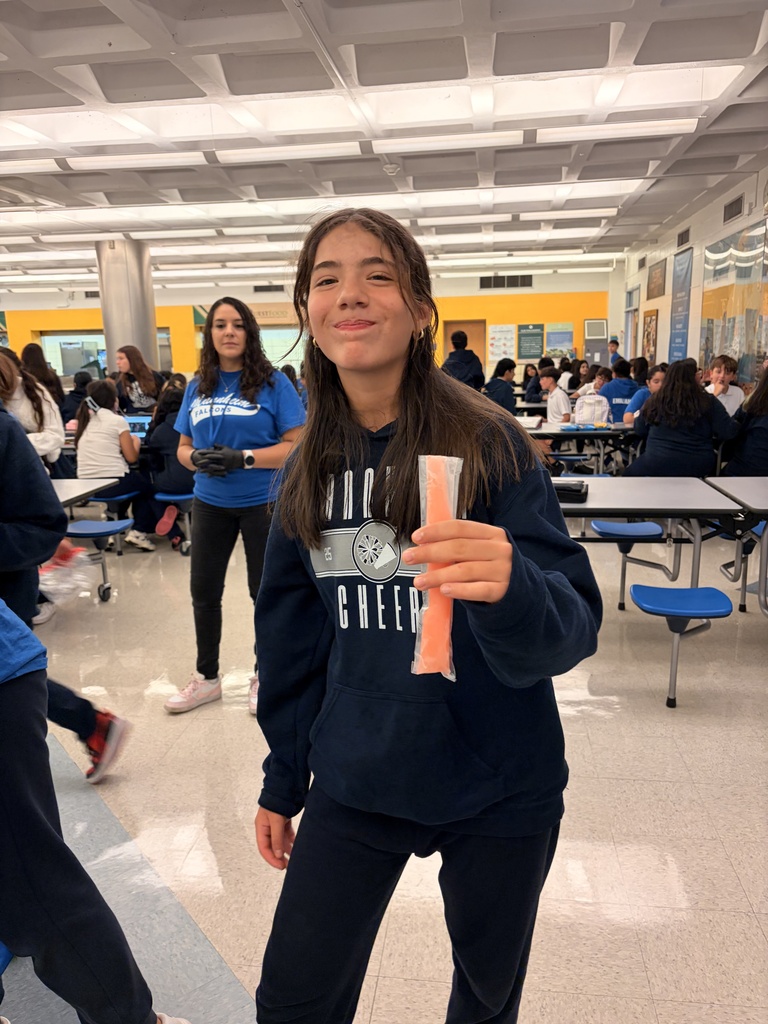 student holding popsicle while smiling in a cafeteria