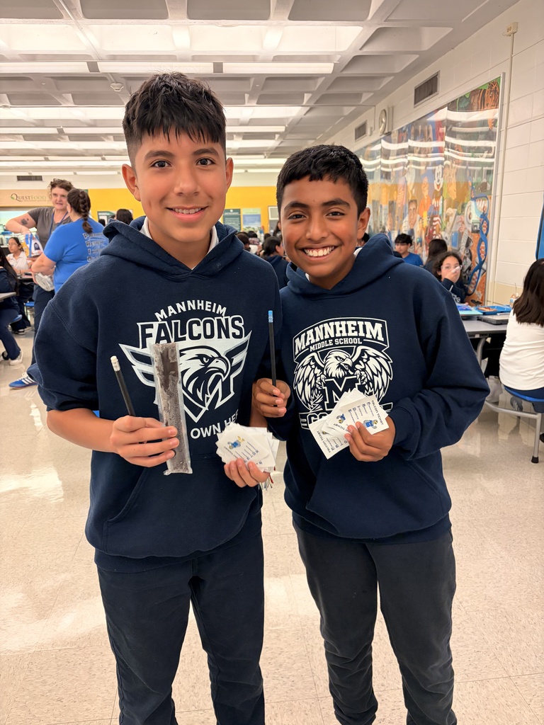 Two students holding popsicle while smiling in a cafeteria, one student is holding a pencil and smiling and holding paper