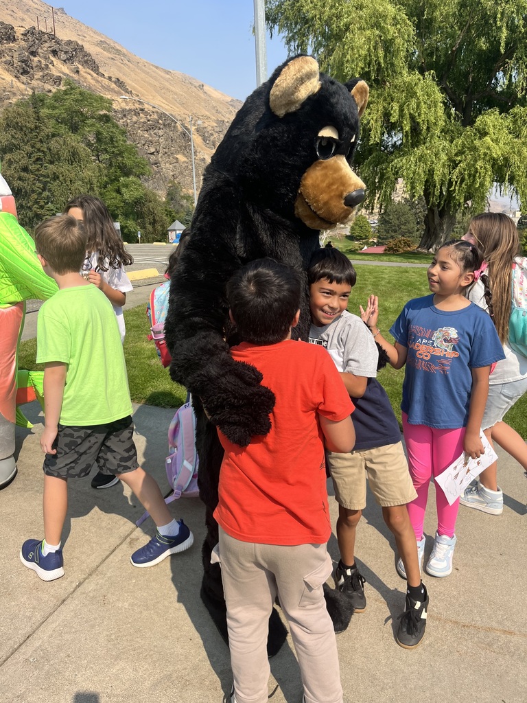 Students getting a hug from a mascot bear.