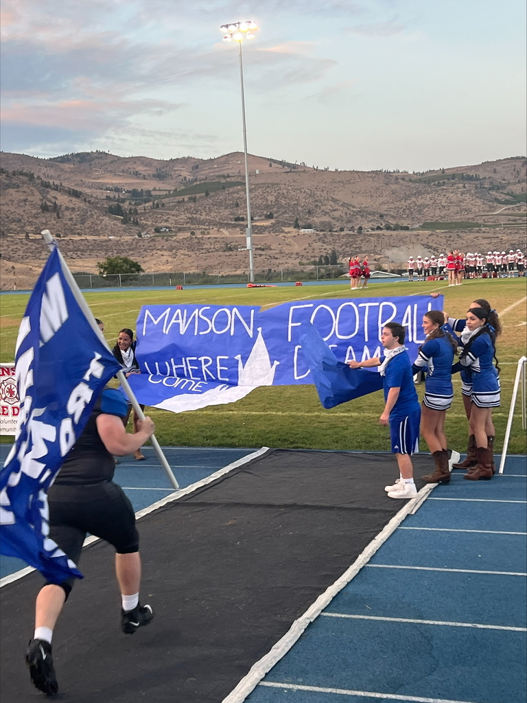 Football player running toward banner.