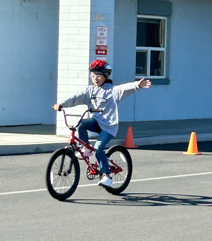 Girl on a bike practicing a left-hand turn signal.