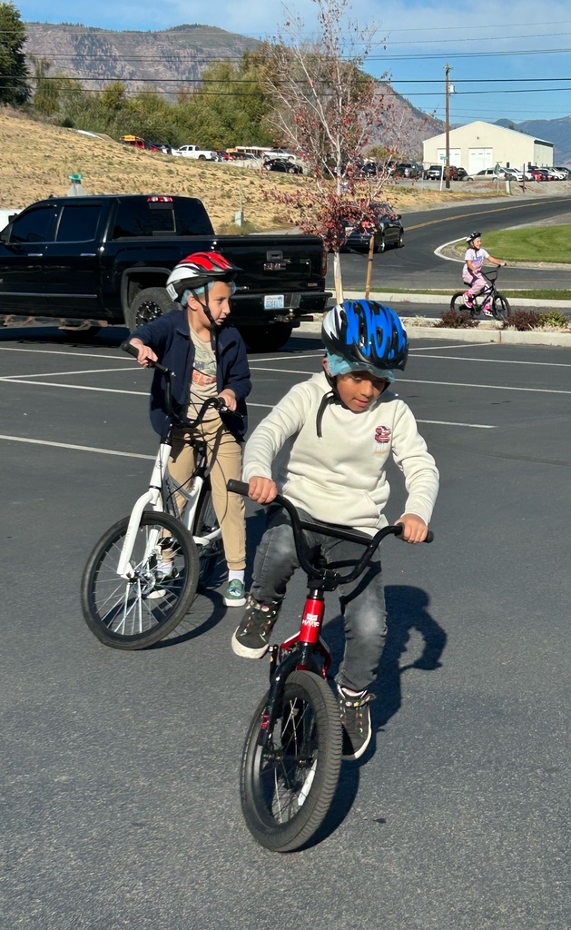 Boys practicing turns on bikes in the elementary school parking lot.