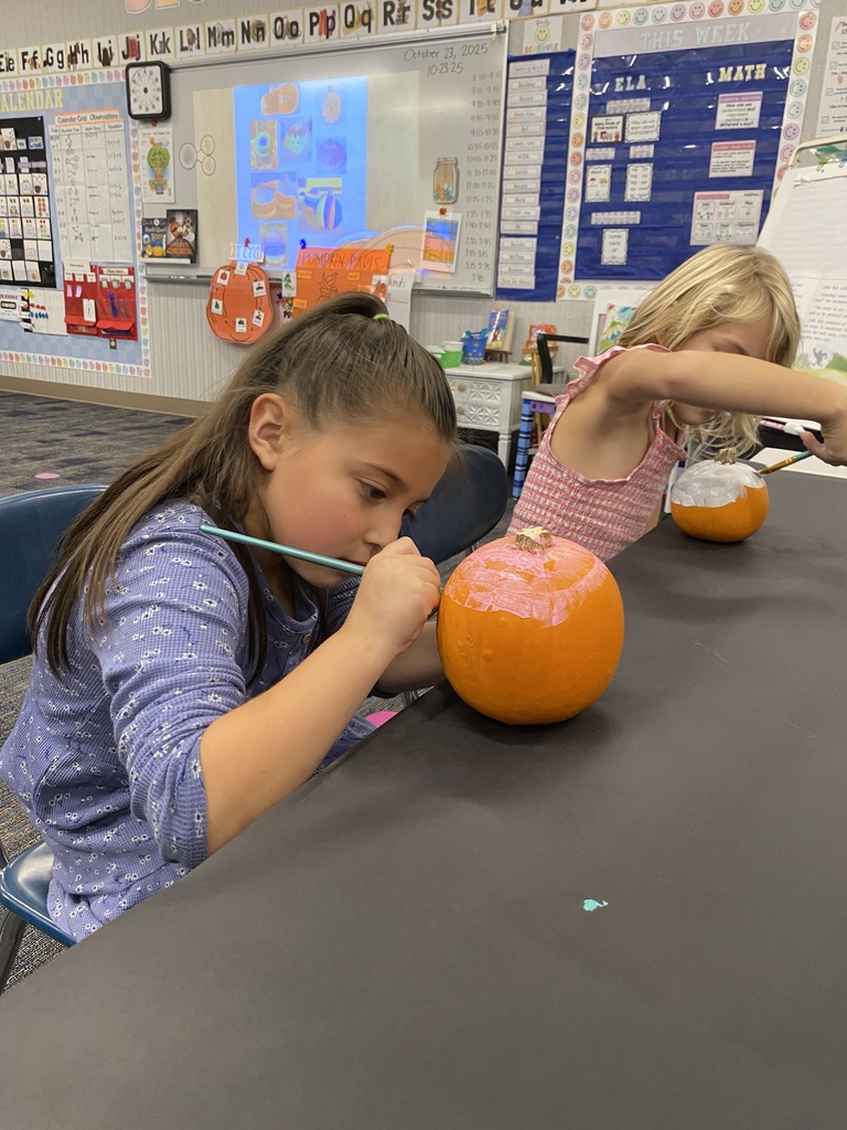 Two girls painting pumpkins.