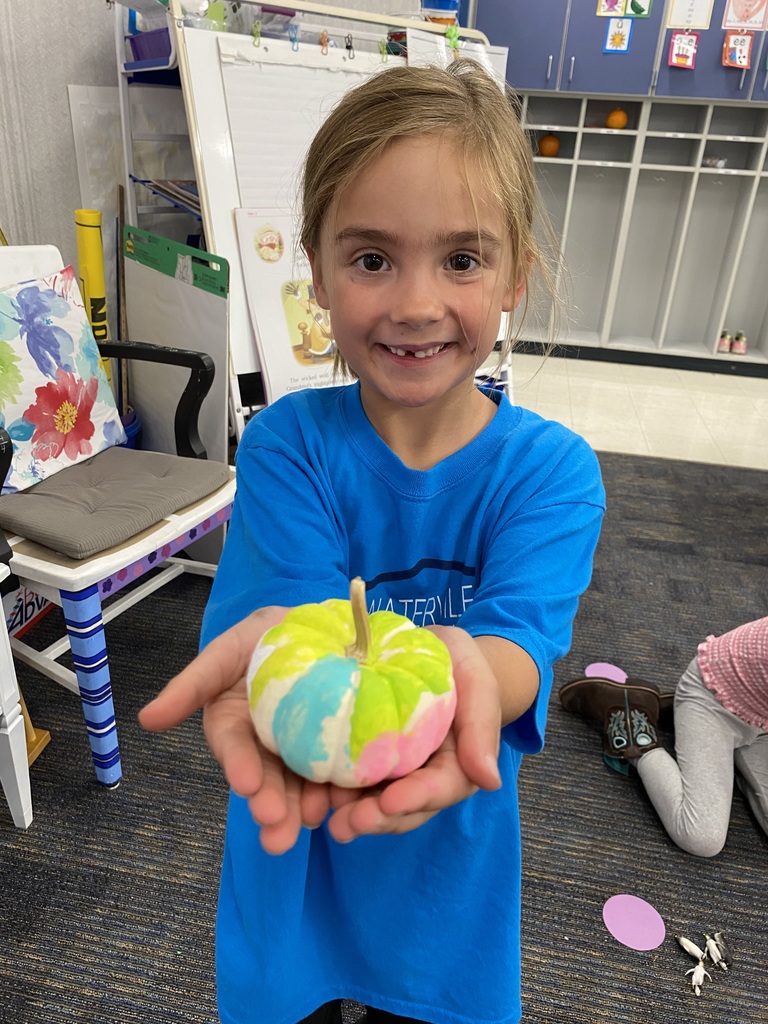 Girl holding a painted pumpkin.