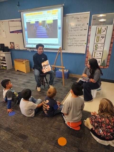 Eighth-grade leadership student reading his own book to students.