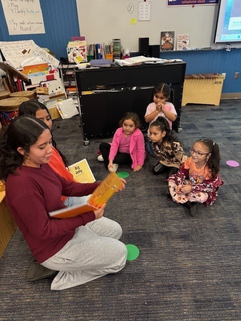 Two more middle school girls read a book they created to elementary students.
