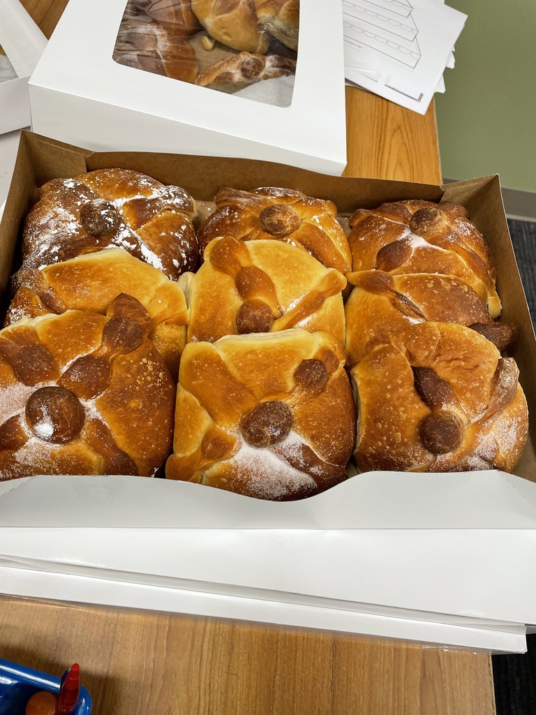 Box of fresh Pan de Muerto sits on a desk.
