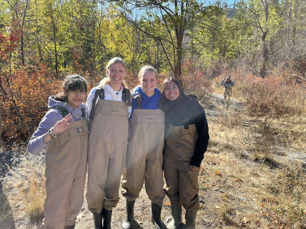 Four Manson high school girls dressed in waders near the river bank.