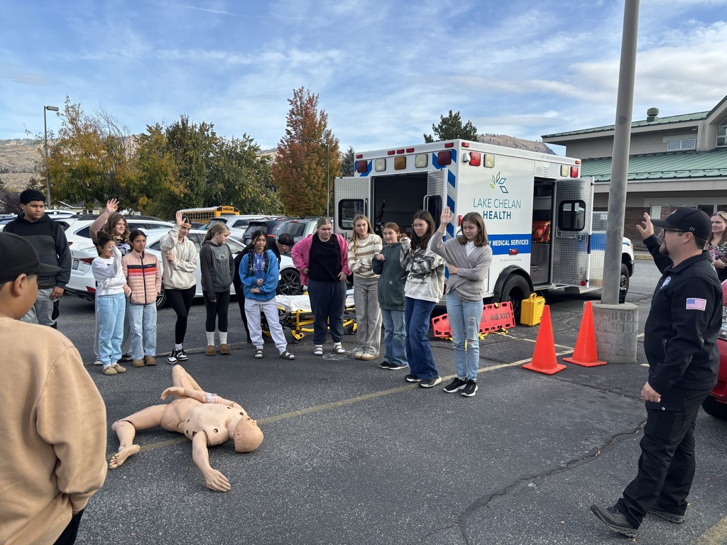 Students stand by an ambulance and answer questions with a paramedic.