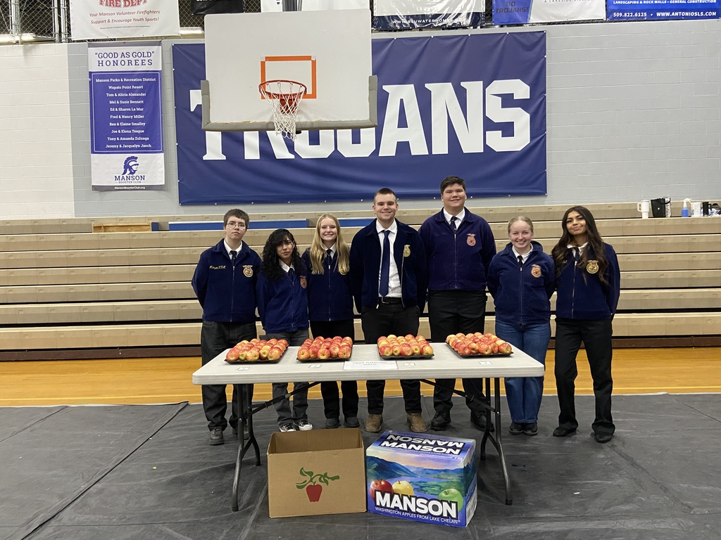 Manson FFA's apple judging team stand before trays of apples.