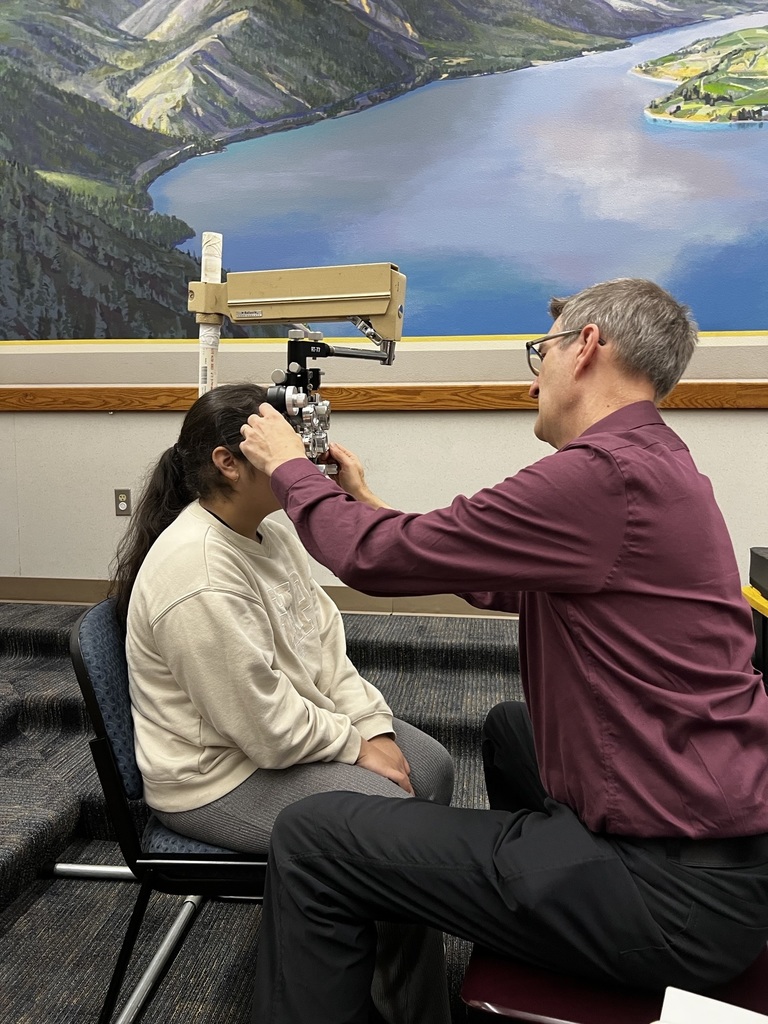 Dr. Pearson performs an eye exam on a female student.