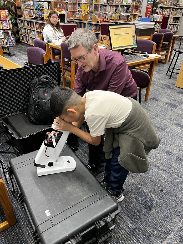 Dr. Pearson has student look through a microscope.
