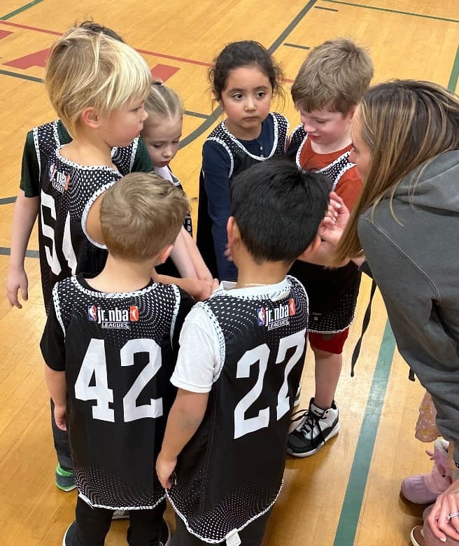 elementary aged basketball players in a  huddle.