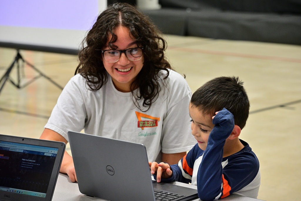 Two students laugh about something on their computer.