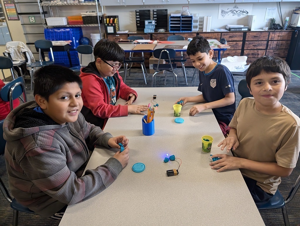 Four students working with Playdough to make hearts.