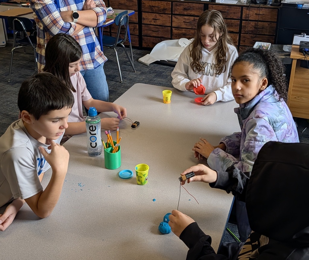 Four students work with batteries to charge Playdough hearts.