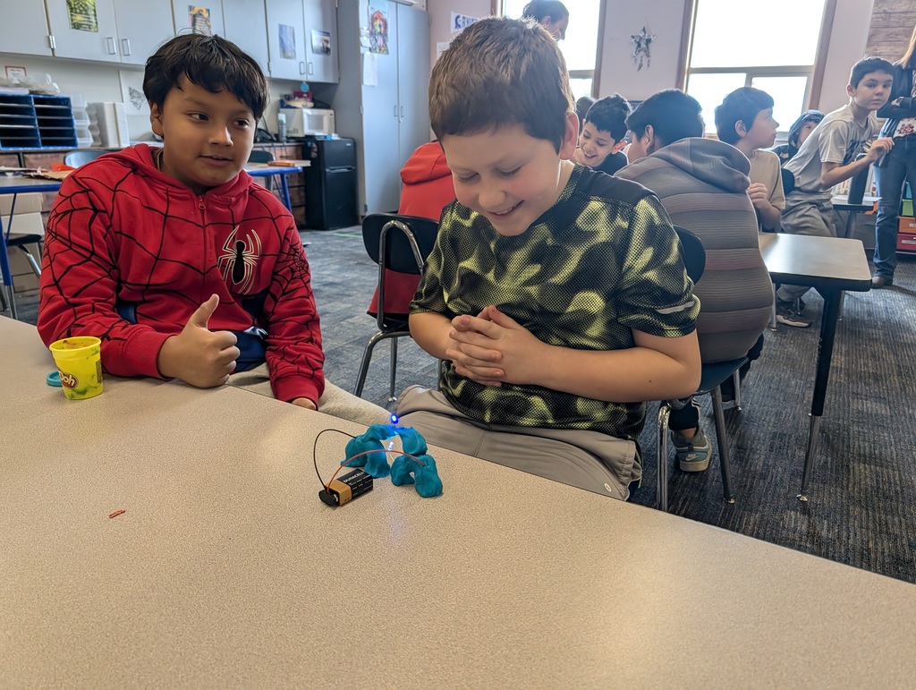 Two boys make a simulated heart with playdough.