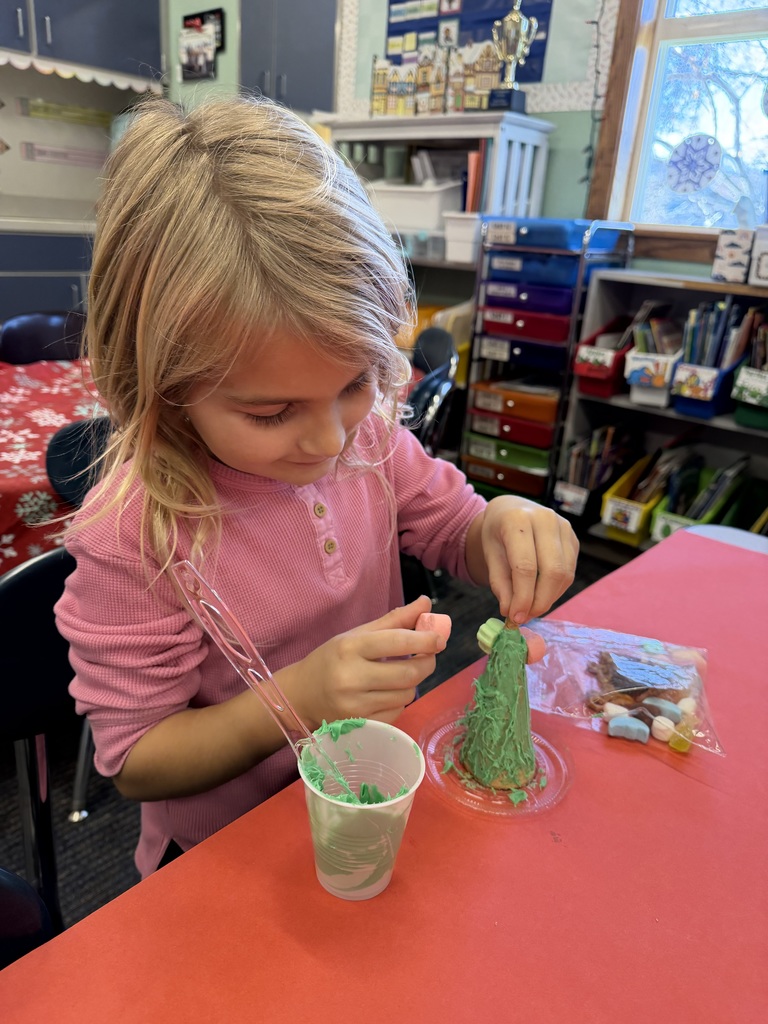 A little girl in a pink shirt adds candy to a candy Christmas tree.