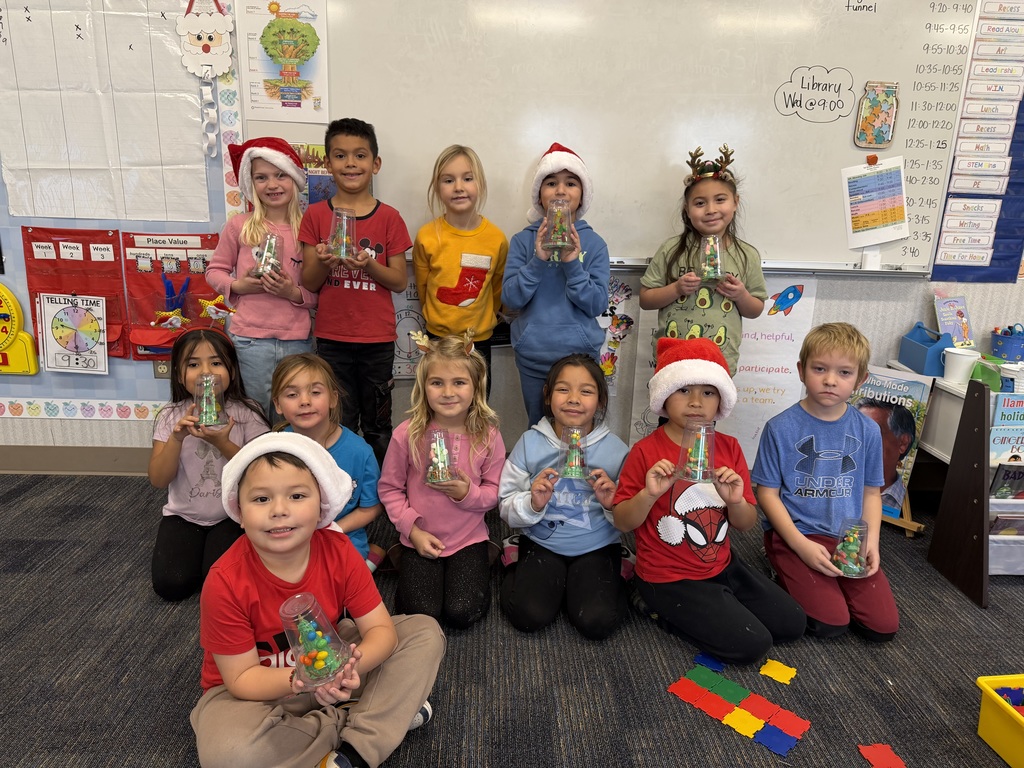 First grade students pose with their finished candy Christmas trees.