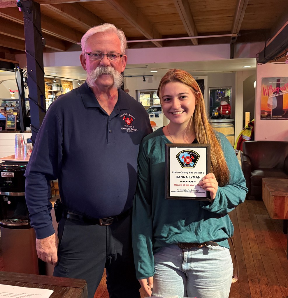 Fire chief stand with recruit of the year for 2025 holding a plaque.
