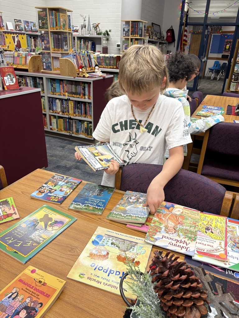 A boy sifts through a desk full of books.