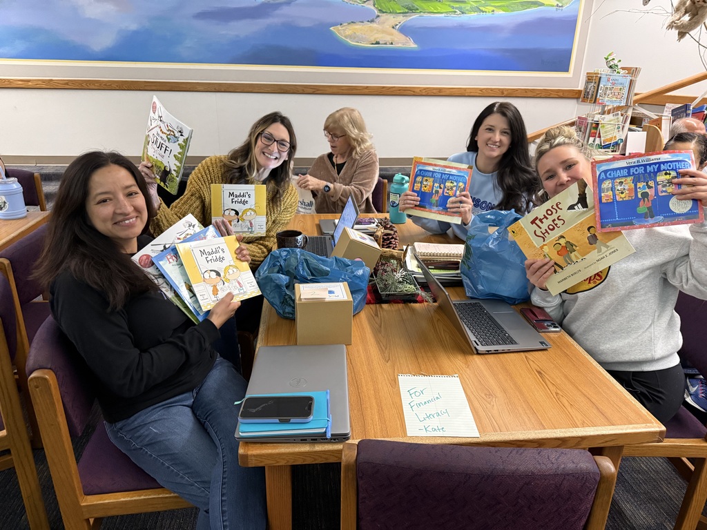 Elementary school teachers hold up books in the library.
