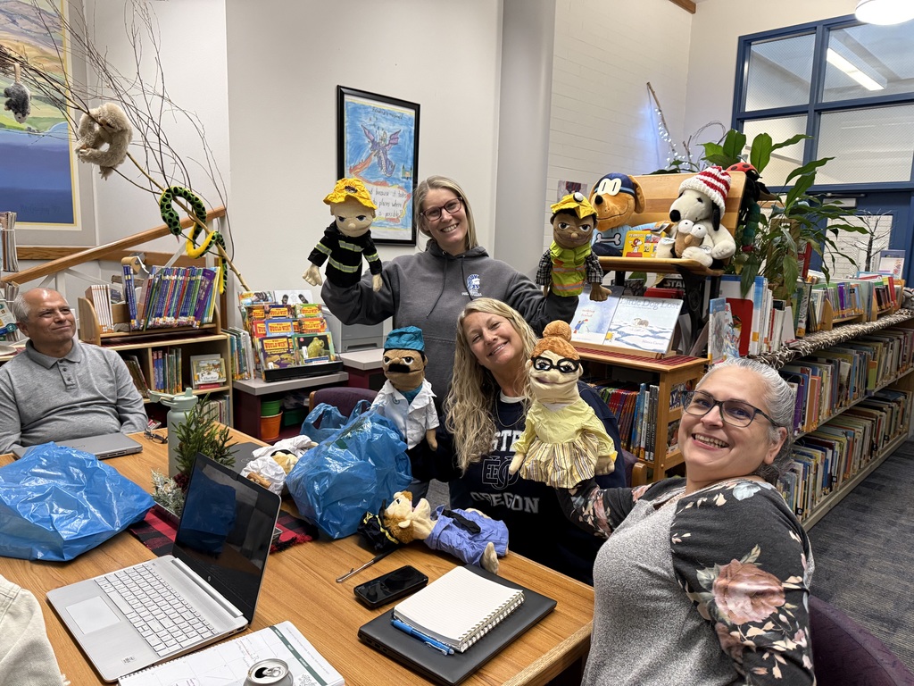 Teachers display puppets on their hands in the library.