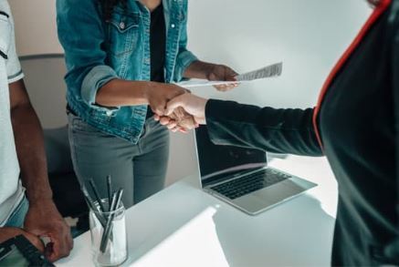 Two people shaking hands over a desk.