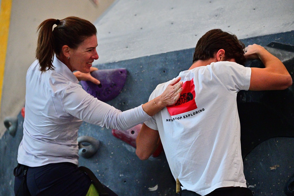 Mom comforts scared son on rock climbing wall.