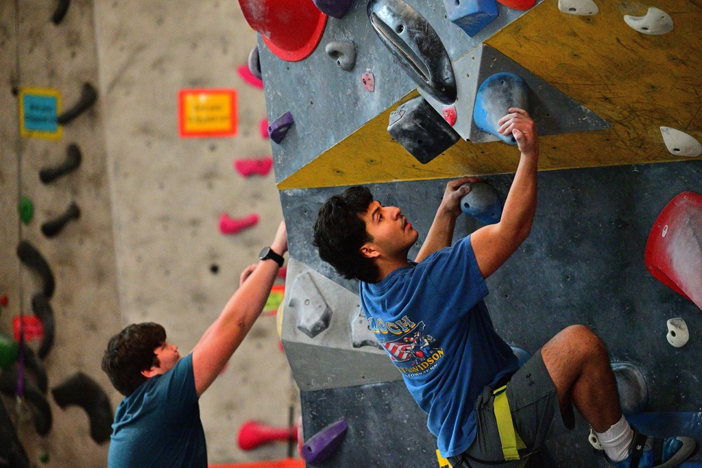 Two male Manson students scale a pitch at the climbing gym.