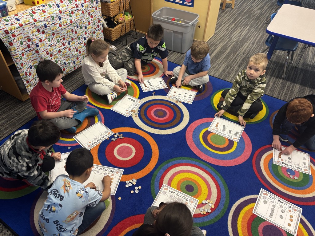 View of students counting coins on a rug.