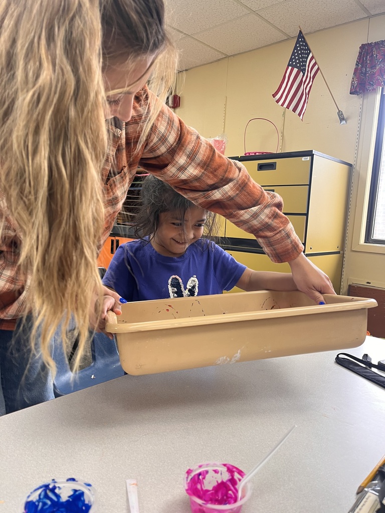 Student rolling paint covered marbles on paper.