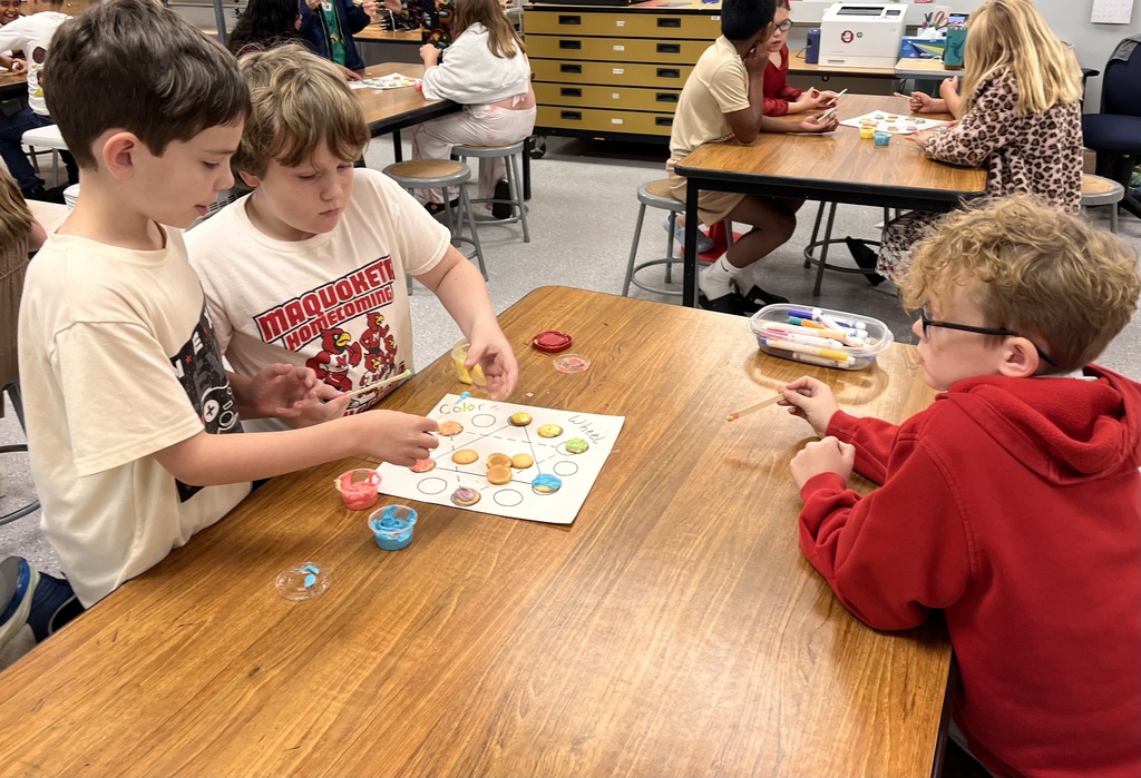 Kids are mixing colors of frosting to make the colors on the color wheel.