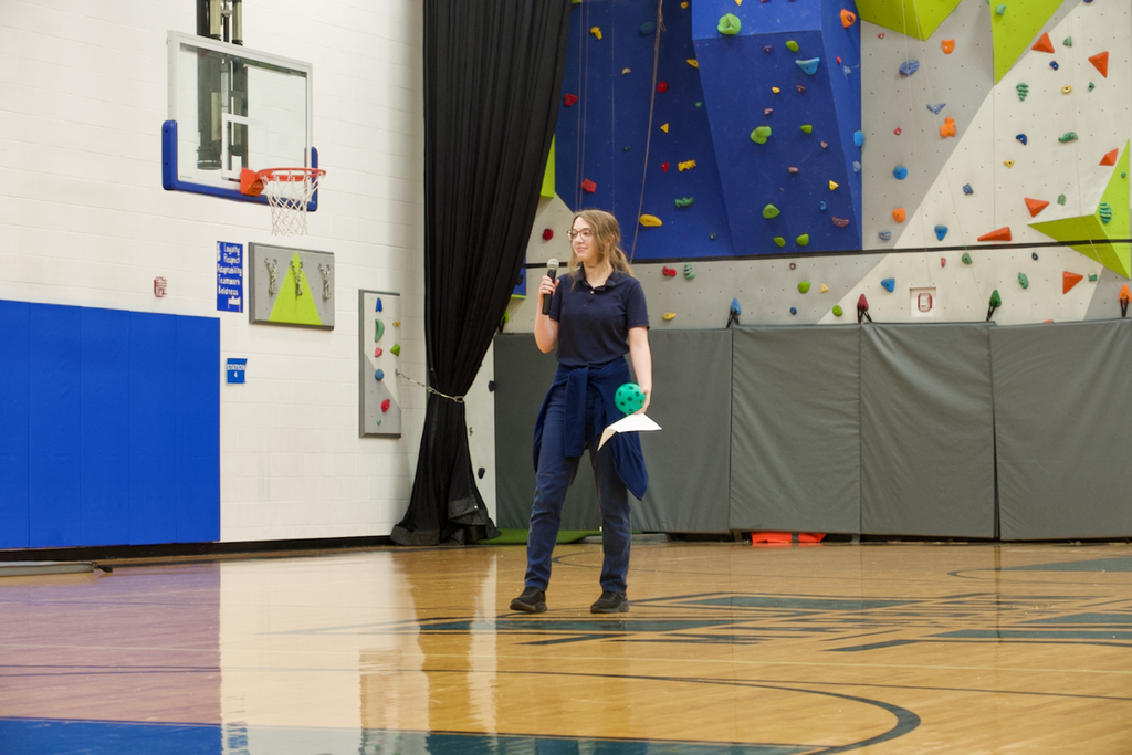 Student standing in the gym talking into a microphone.