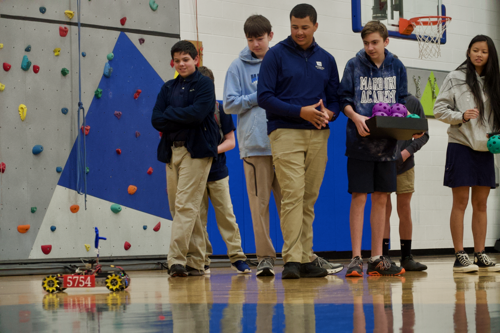 Students looking at a robot on the floor.