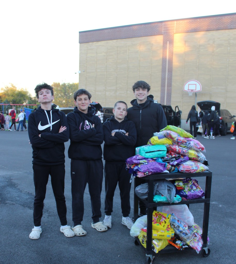 4 mcms students standing in front of a bags of candy for truck or treat 
