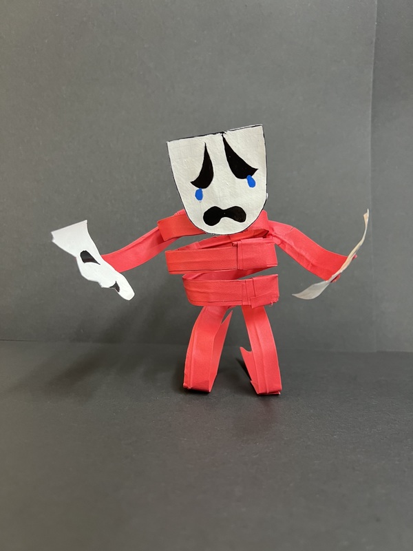 Red Paper Figure – Front View: A red paper character with a sad face and blue tears stands holding torn white paper pieces.