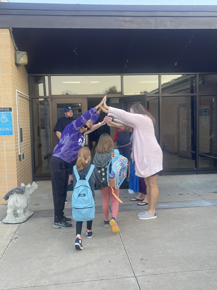 Several teachers giving high fives to students as the enter the MES building.