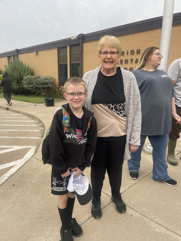 A grandma and her grandson take a picture as she is greeting students