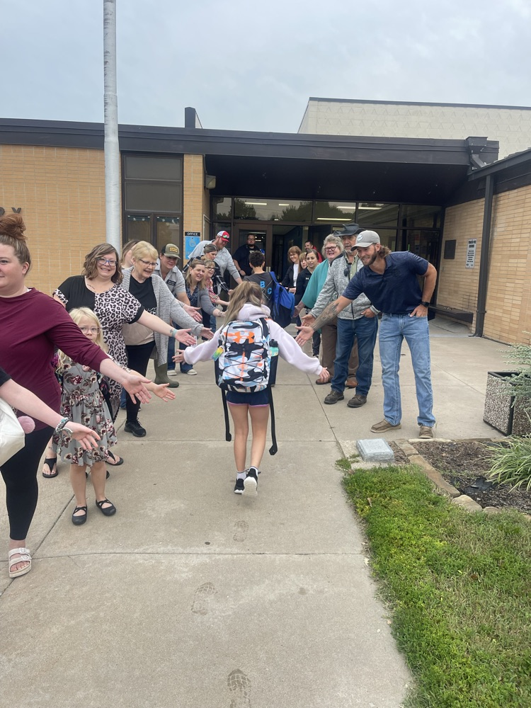 A couple of students high five the line of greeters as the walk into the school