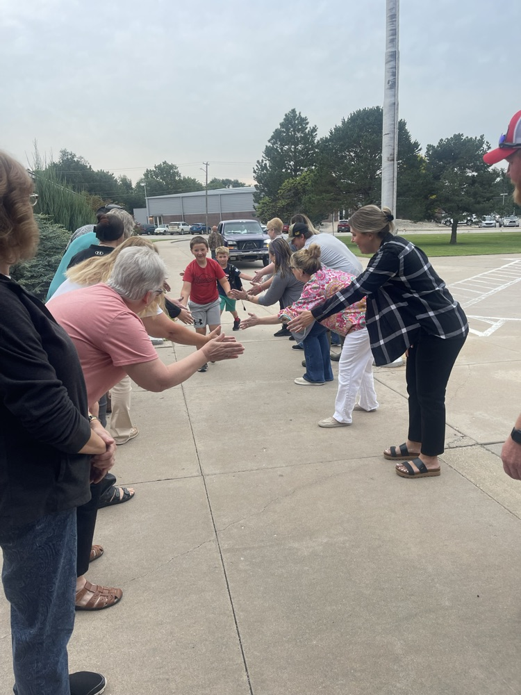 A couple students high fiving the greeters as they are walking into the school