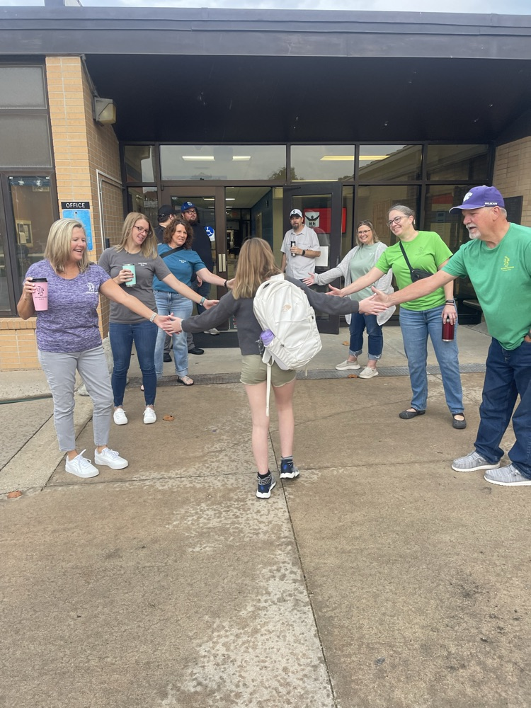 Greeters high five students as they get to school