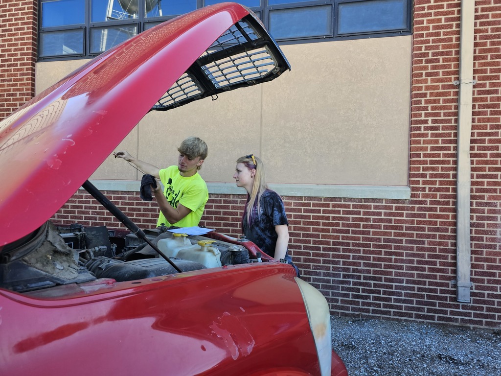 Wyatt and Aury check the oil on a truck.