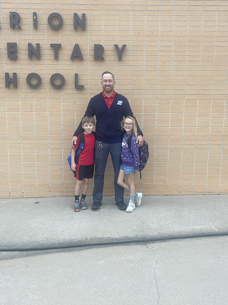 A father posing for a picture with his son and daughter in front of the MES building.