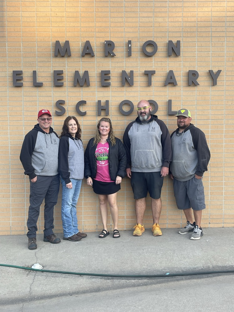 Employees of Marion Marble and Granite take a picture in front of Marion Elementary School.