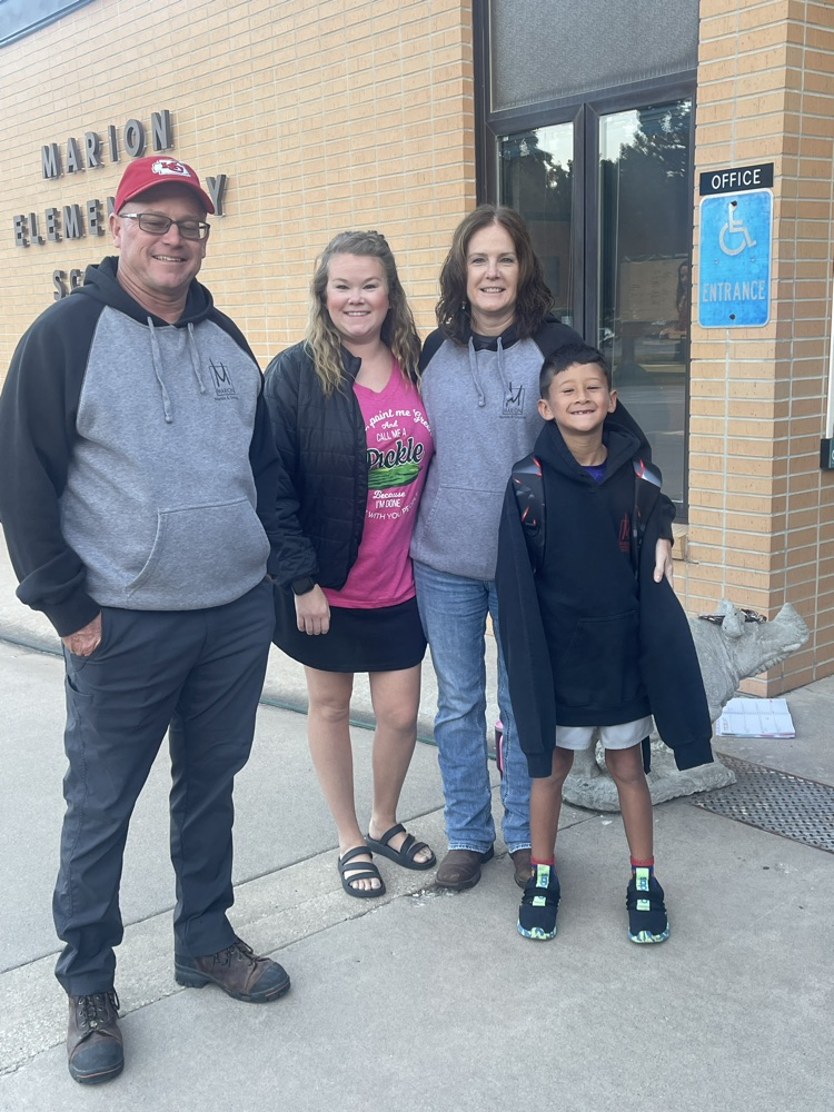 A MES student takes a picture with his mom and his grandparents who greeted students this morning.