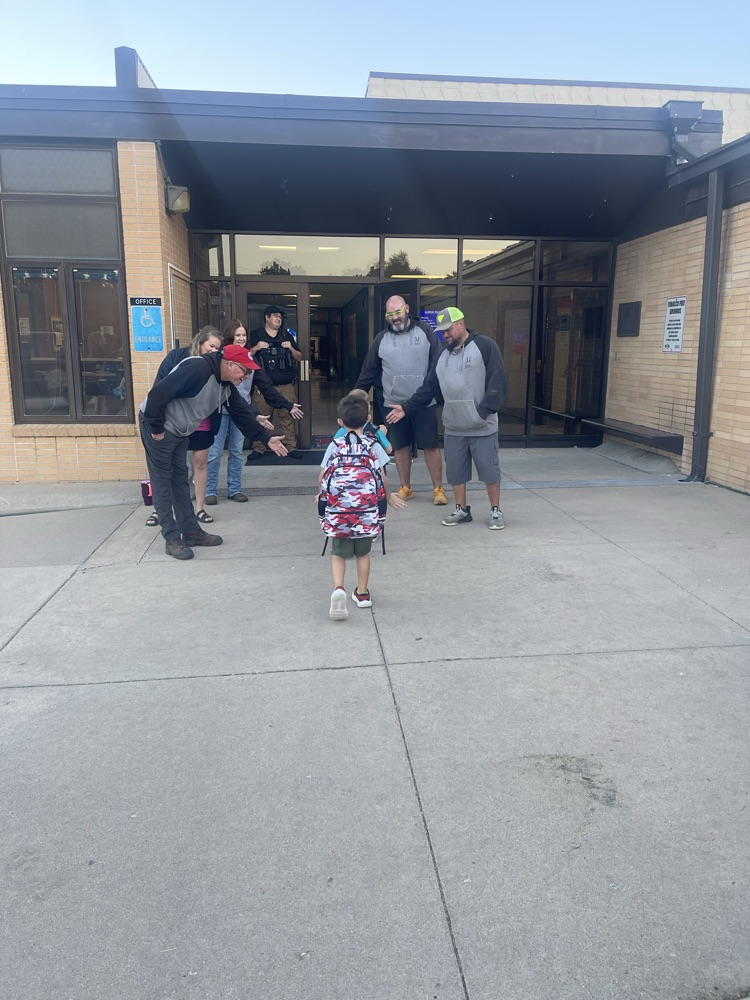 Greeters high five students as they enter the building this morning.